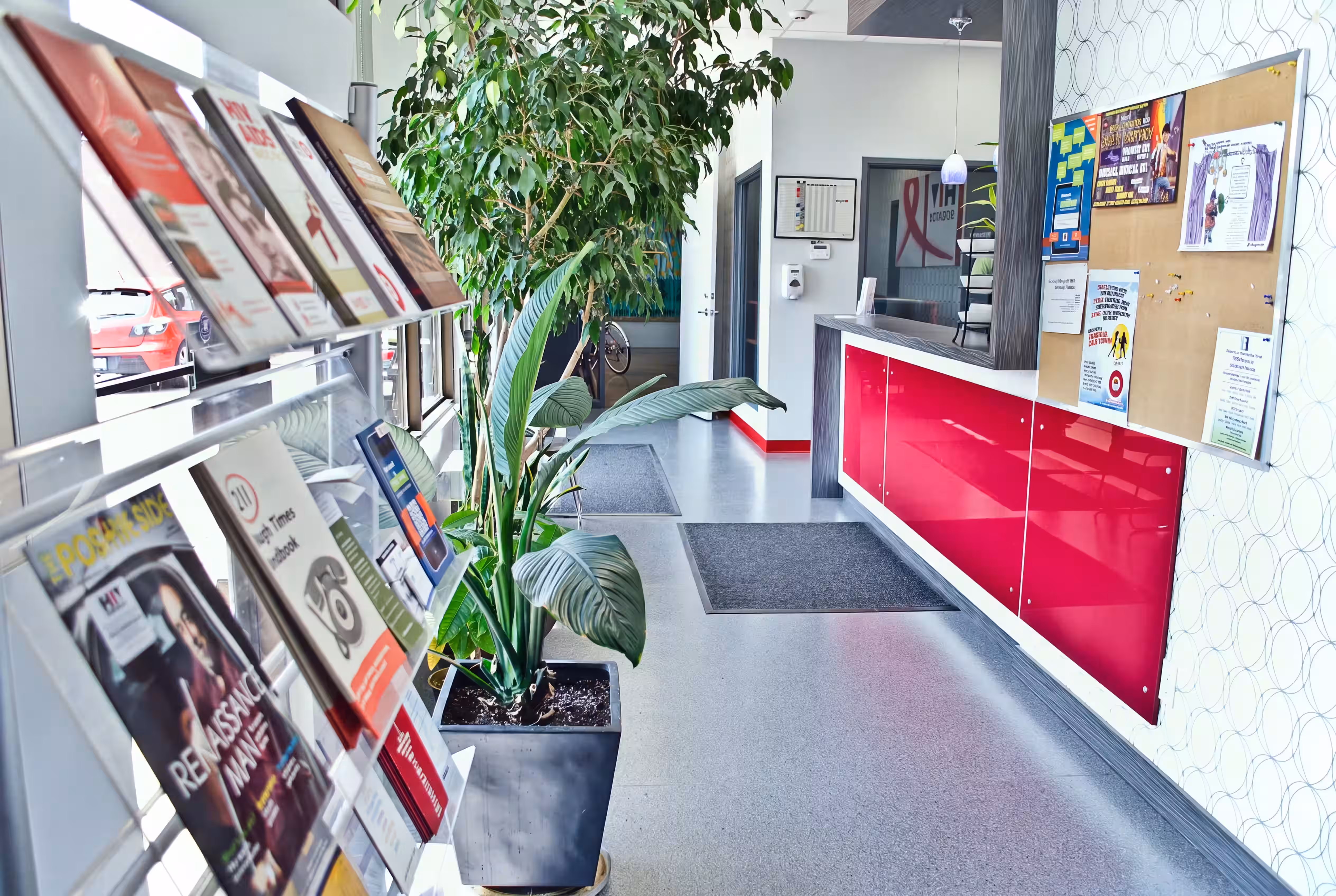 HIV Edmonton reception area with a red front desk, brochure racks, and a potted plant